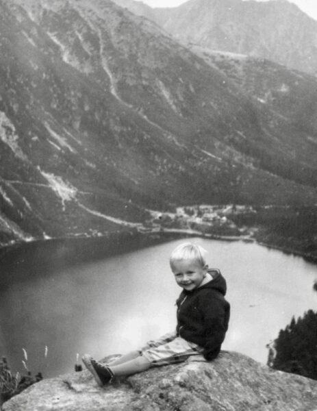 Svartvitt barnporträtt av Ariana Ramhage, sittande i bergen, på hög höjd under en vandringstur.