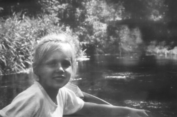 Svartvitt barnporträtt av Ariana Ramhage som en ung flicka, sittande i en kajak på vattnet.