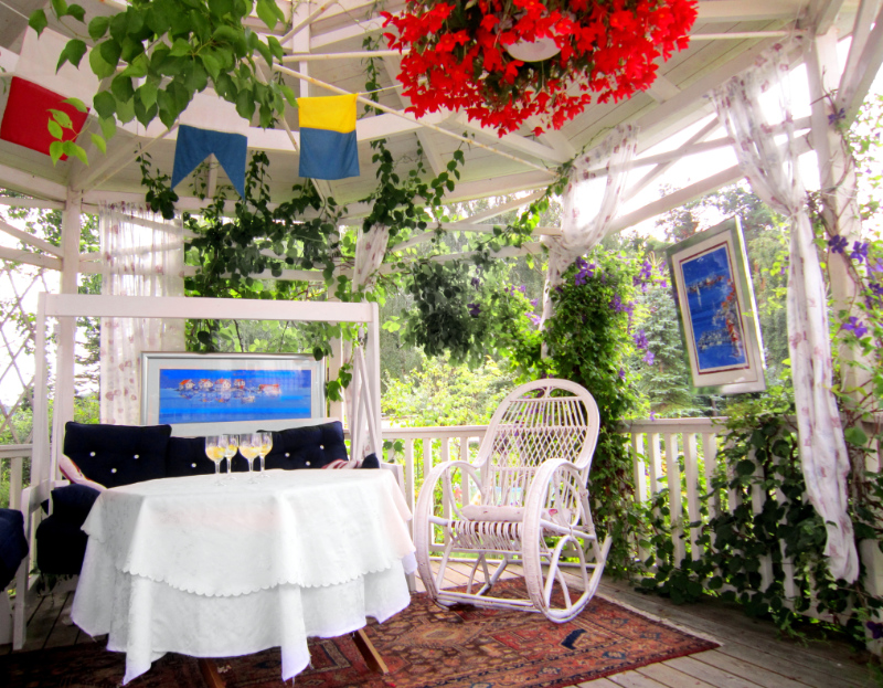 Tavlorna hänger i lusthuset. I hela trädgården hänger tavlor, bakom varje buske.